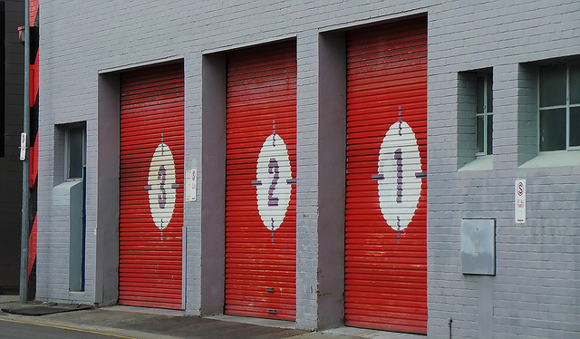 Three garage doors with the numbers three, two, and one painted on them