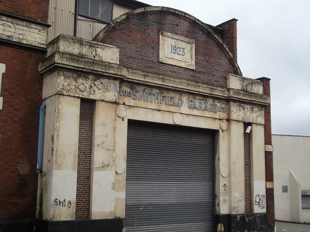 old garage door that is surrounded by a thick and ornate brick building